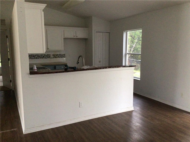 kitchen with sink, dark wood-type flooring, white cabinetry, tasteful backsplash, and vaulted ceiling