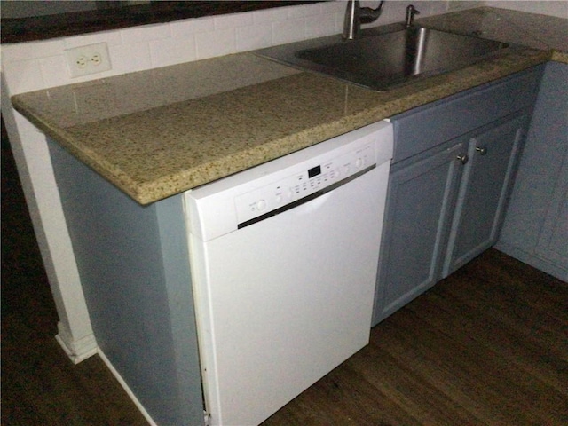 kitchen with sink, dark stone countertops, backsplash, dark hardwood / wood-style flooring, and white dishwasher