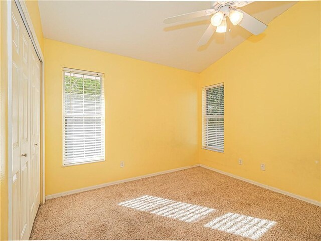 unfurnished bedroom featuring carpet flooring, ceiling fan, vaulted ceiling, and a closet