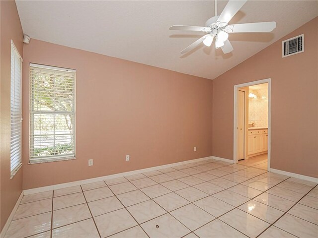 spare room featuring ceiling fan, light tile patterned floors, lofted ceiling, and a wealth of natural light