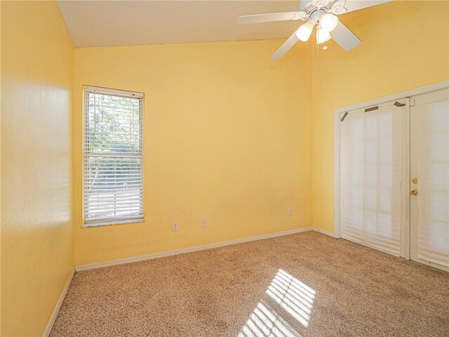 unfurnished bedroom with ceiling fan, vaulted ceiling, carpet floors, and multiple windows