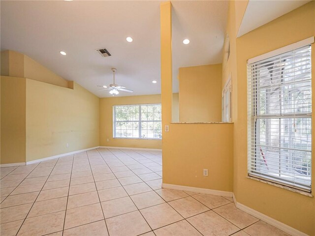 empty room with vaulted ceiling, ceiling fan, and light tile patterned flooring