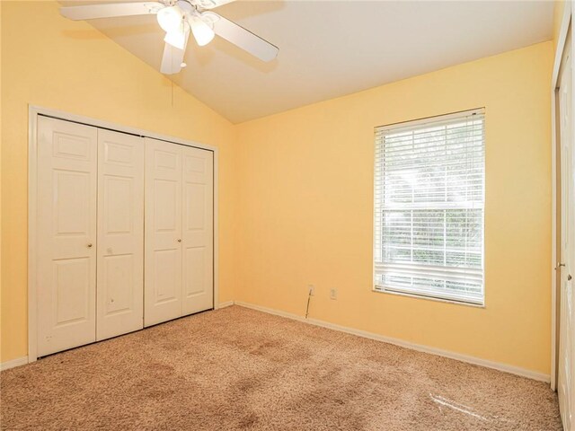 unfurnished bedroom featuring carpet flooring, ceiling fan, a closet, and vaulted ceiling