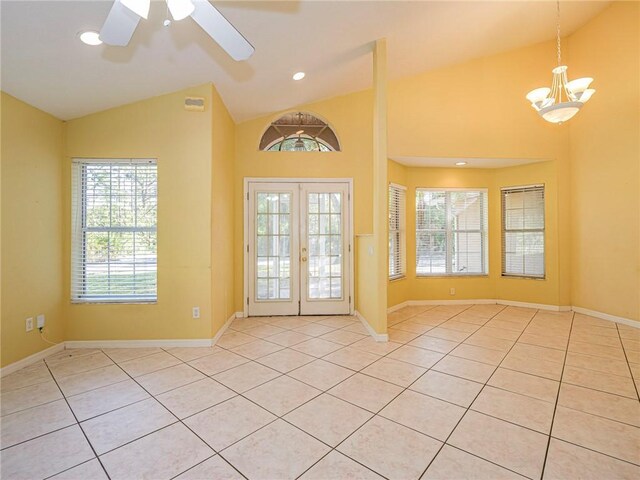 foyer featuring ceiling fan with notable chandelier, vaulted ceiling, light tile patterned floors, and french doors