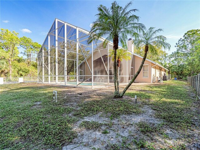 back of property featuring a lanai, a yard, and central AC unit