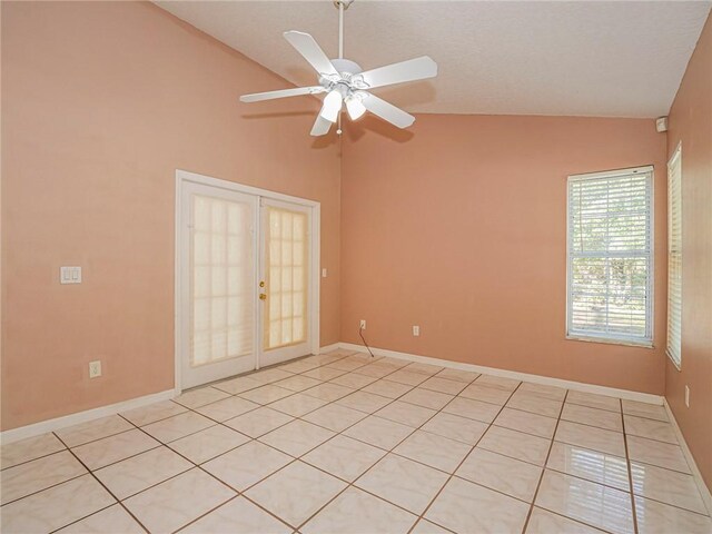 empty room featuring ceiling fan, french doors, light tile patterned floors, and lofted ceiling