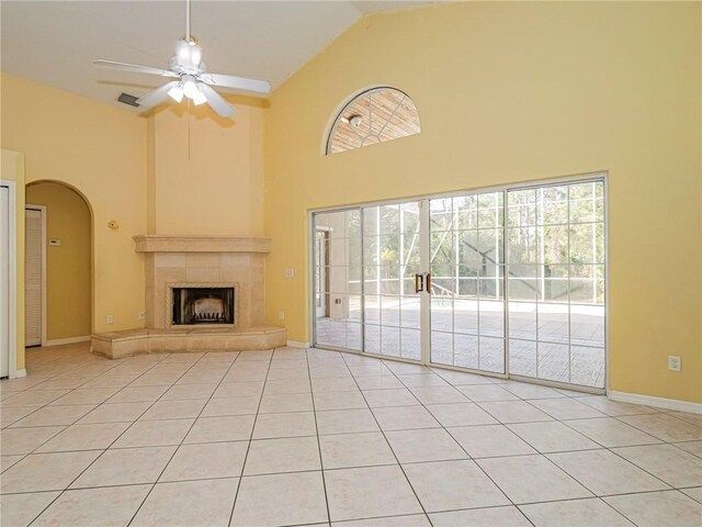 unfurnished living room featuring a tile fireplace, ceiling fan, high vaulted ceiling, and light tile patterned floors