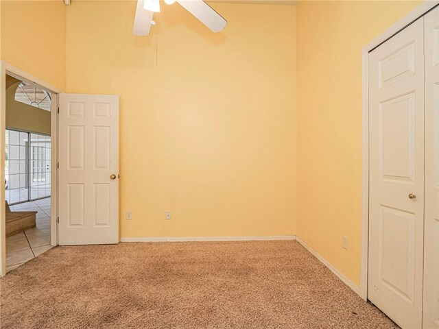 carpeted spare room featuring ceiling fan and a high ceiling