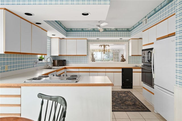 kitchen with white cabinetry, sink, white appliances, and a tray ceiling