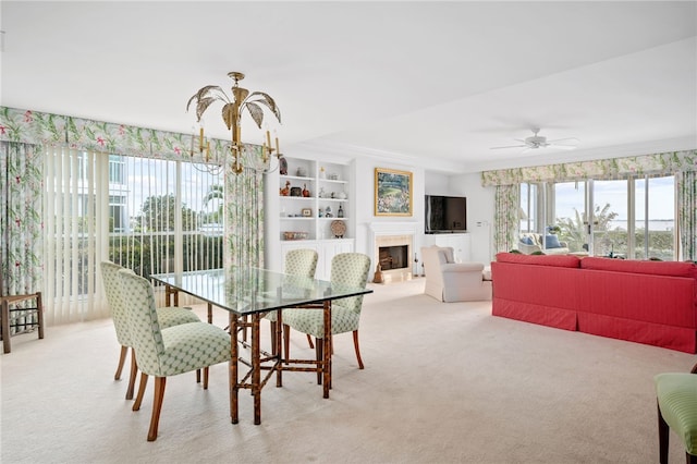 dining area featuring ceiling fan with notable chandelier, light colored carpet, and built in features