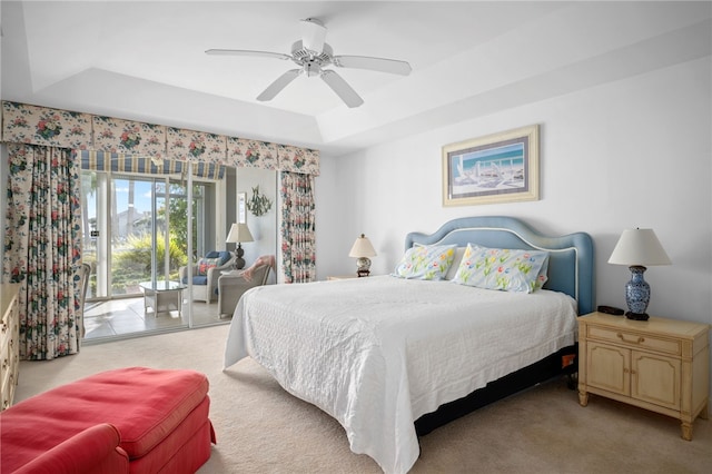 carpeted bedroom featuring access to outside, ceiling fan, and a tray ceiling