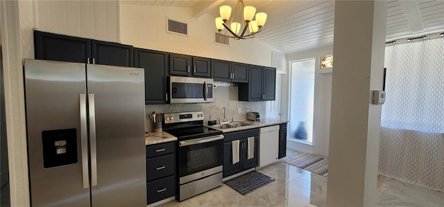 1825 4th Ln, Vero Beach, FL 32962 - kitchen with stainless steel appliances, a chandelier, dark cabinetry, tasteful backsplash, and hanging light fixtures