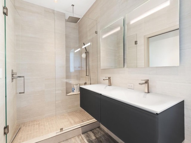 bathroom with backsplash, walk in shower, vanity, wood-type flooring, and tile walls