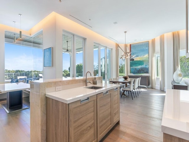 111 Mariner Beach Ln, Vero Beach, FL 32963 - kitchen featuring light wood-type flooring, light countertops, a chandelier, and a center island with sink