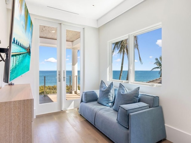 living room with plenty of natural light, a water view, and light hardwood / wood-style flooring