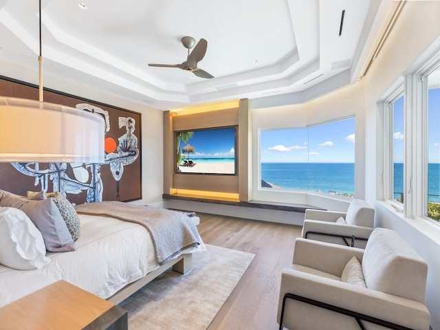 bedroom featuring a tray ceiling, ceiling fan, and light hardwood / wood-style flooring