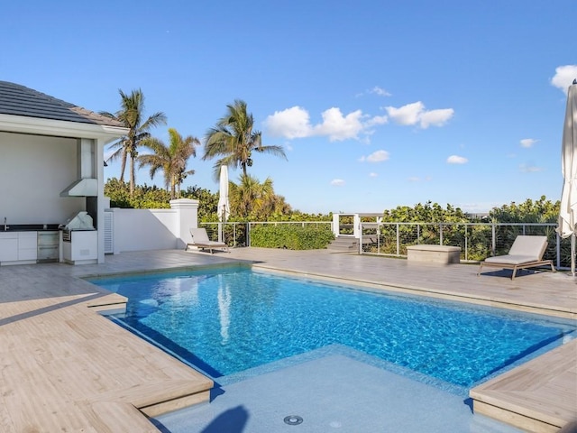 view of pool with an outdoor kitchen and a patio area