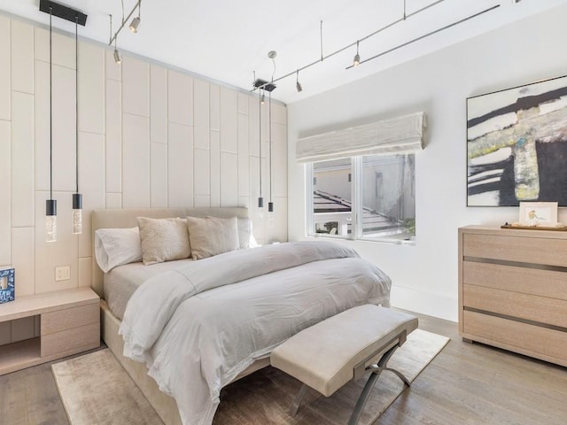 bedroom with track lighting and light hardwood / wood-style flooring