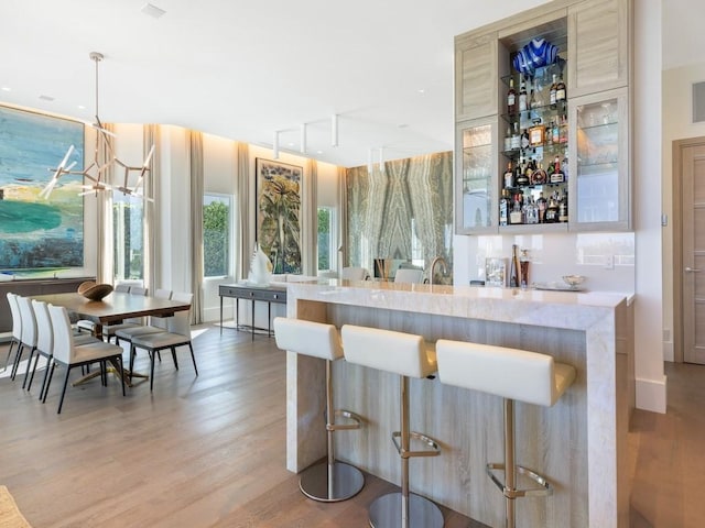 bar featuring a chandelier, wood-type flooring, hanging light fixtures, and sink