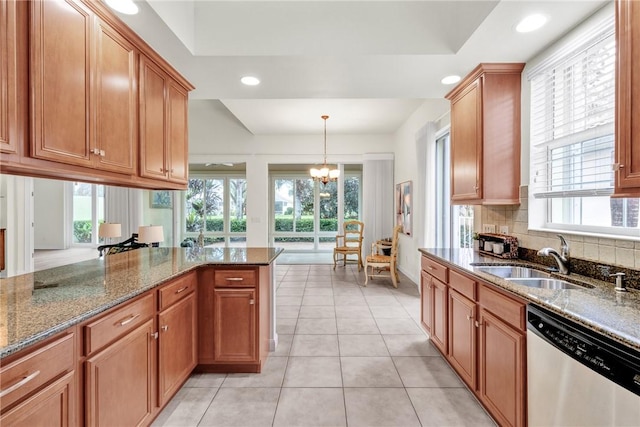 kitchen with a notable chandelier, dishwasher, sink, decorative light fixtures, and dark stone counters