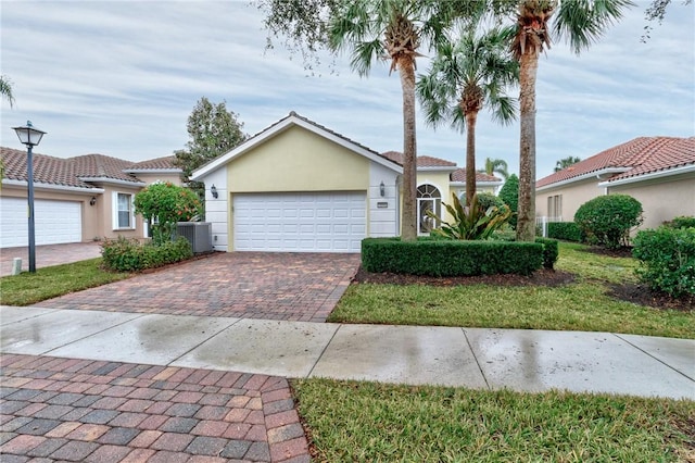 view of front of home featuring a garage, a front yard, and central air condition unit