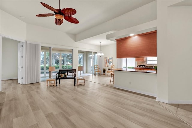 unfurnished living room with ceiling fan with notable chandelier and light hardwood / wood-style flooring