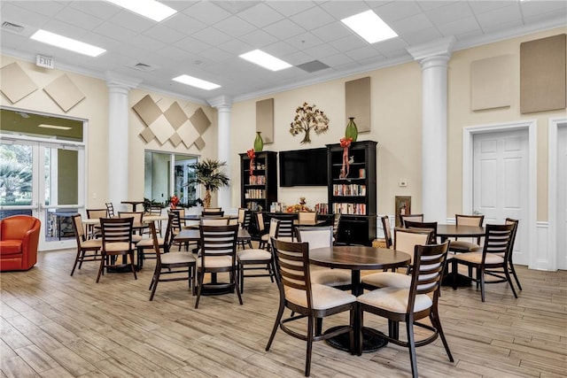 dining area featuring ornamental molding, french doors, light hardwood / wood-style flooring, and ornate columns