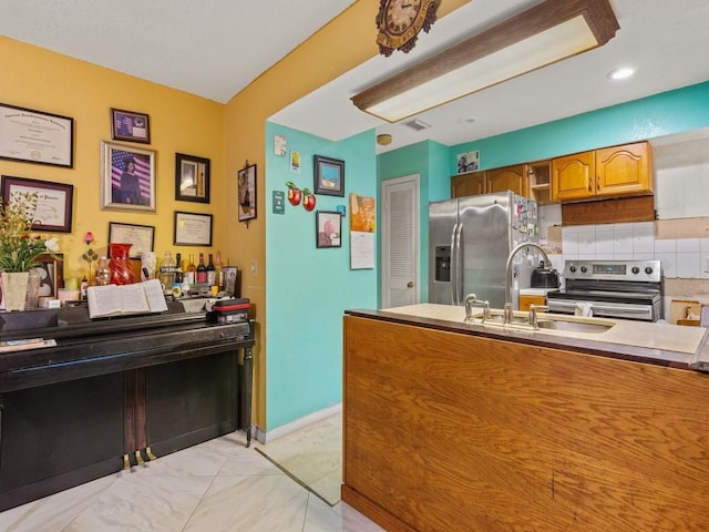 663 20th Pl SW, Vero Beach, FL 32962 - kitchen featuring stainless steel appliances, brown cabinets, tasteful backsplash, light countertops, and light marble finish floors