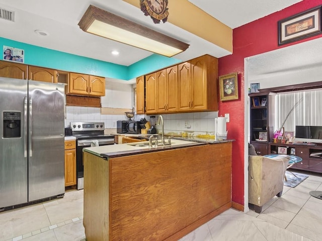 663 20th Pl SW, Vero Beach, FL 32962 - kitchen with stainless steel appliances, brown cabinets, tasteful backsplash, and a peninsula