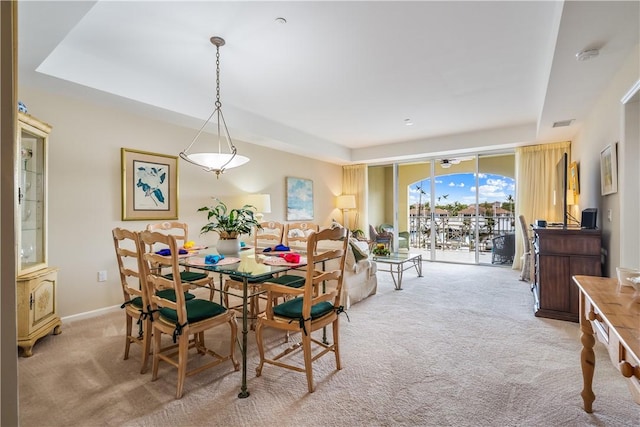 dining room with light carpet and a raised ceiling