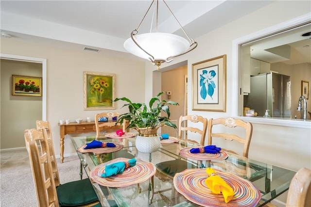 carpeted dining space featuring baseboards, visible vents, and a sink