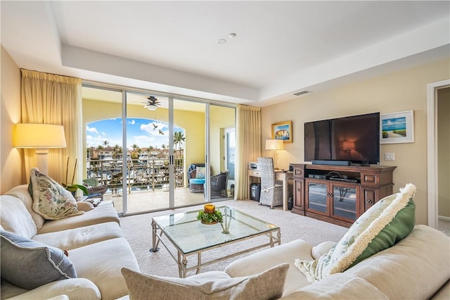 carpeted living room with a tray ceiling and visible vents