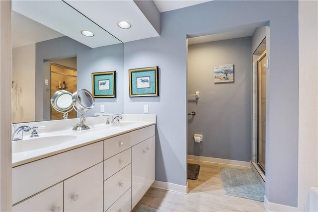 full bath featuring double vanity, a sink, baseboards, and an enclosed shower