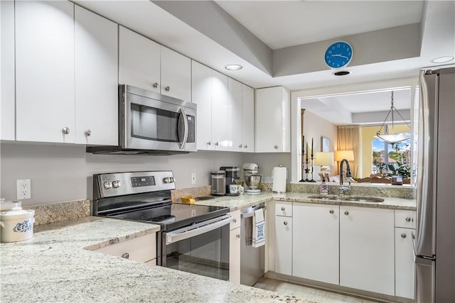 kitchen with white cabinetry, appliances with stainless steel finishes, light stone counters, and a sink