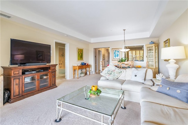 living area with carpet floors, a raised ceiling, and visible vents