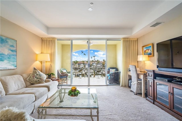 carpeted living area featuring visible vents and a tray ceiling