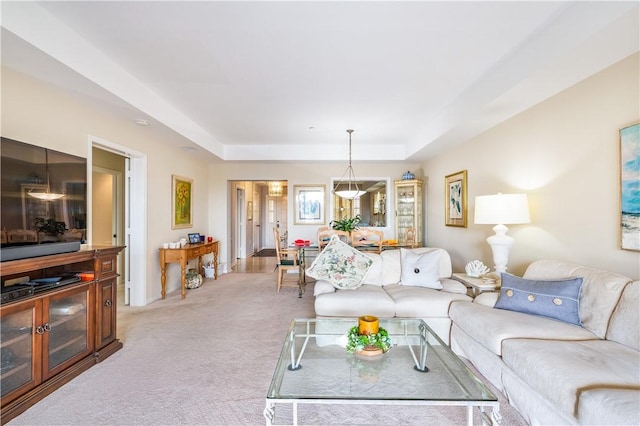 living area featuring light carpet and a tray ceiling