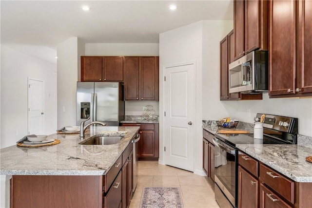 kitchen featuring appliances with stainless steel finishes, light tile patterned flooring, a sink, and light stone countertops