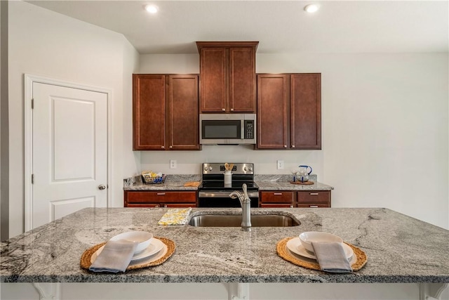 kitchen featuring stainless steel appliances, recessed lighting, a sink, and light stone counters