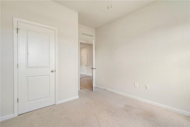 unfurnished bedroom featuring baseboards, visible vents, and light colored carpet