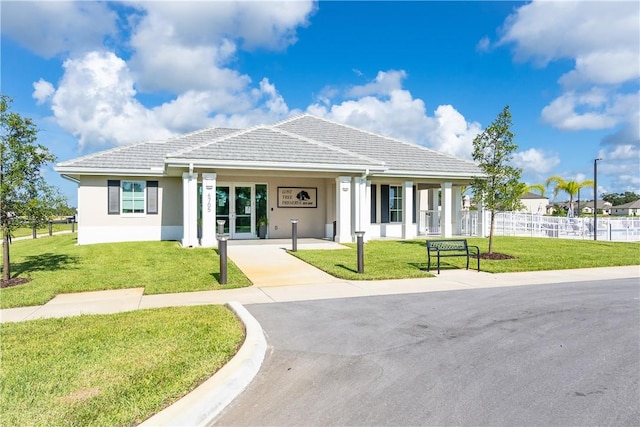 view of front of house with stucco siding, a tile roof, fence, and a front yard