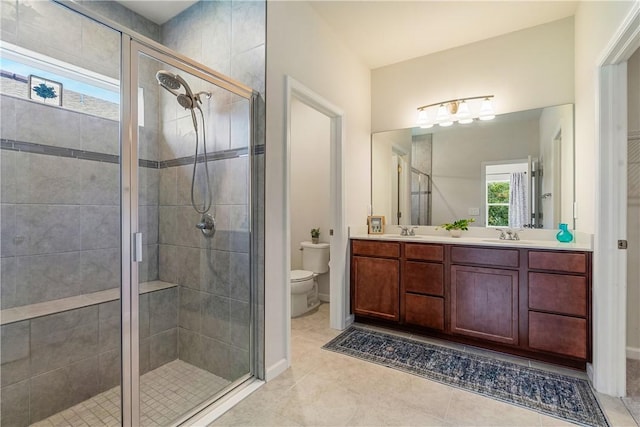 full bathroom with double vanity, toilet, a sink, a shower stall, and tile patterned floors