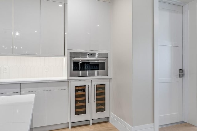 kitchen featuring white cabinetry, wine cooler, tasteful backsplash, light hardwood / wood-style floors, and oven