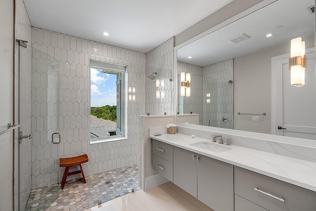 bathroom with tile patterned flooring, vanity, tiled shower, and tile walls