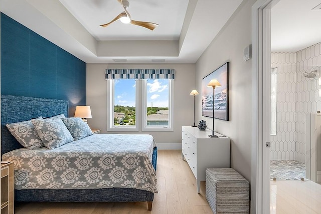 bedroom with a raised ceiling, ceiling fan, and light hardwood / wood-style floors