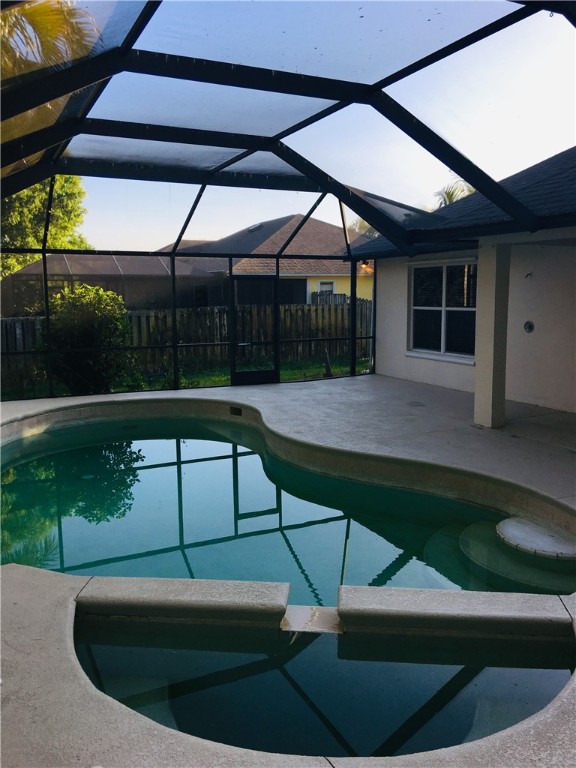 view of swimming pool featuring glass enclosure and a patio area