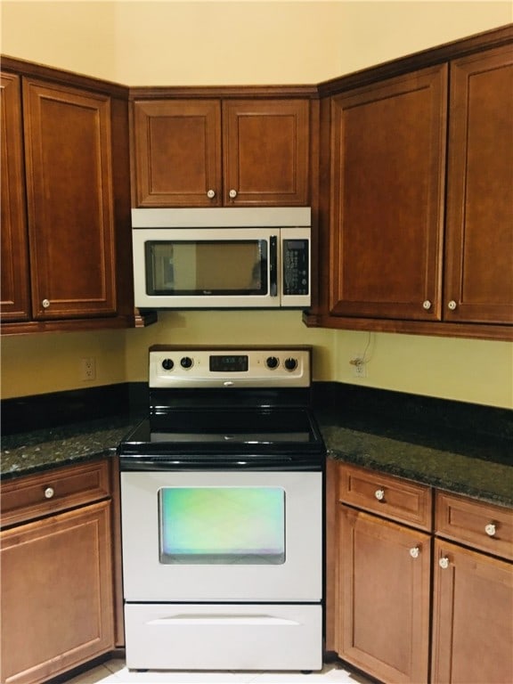 kitchen featuring white electric range oven and dark stone countertops