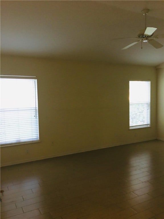 spare room featuring ceiling fan, hardwood / wood-style floors, and a healthy amount of sunlight