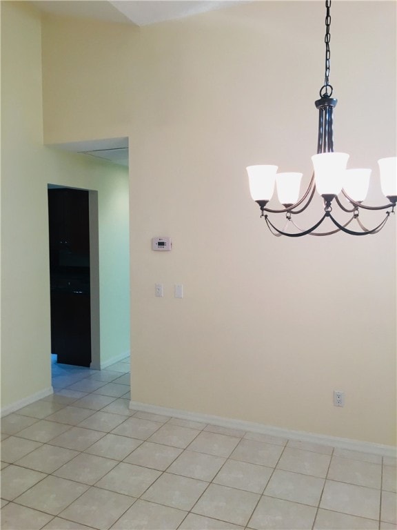 tiled empty room with a notable chandelier