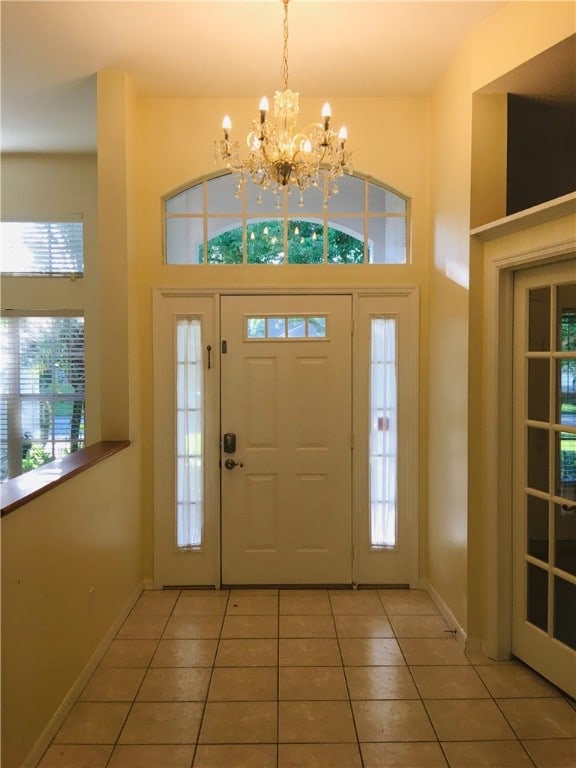 foyer entrance with a towering ceiling, tile patterned floors, and an inviting chandelier